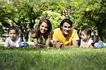 A picture of a family of four with trees on the background